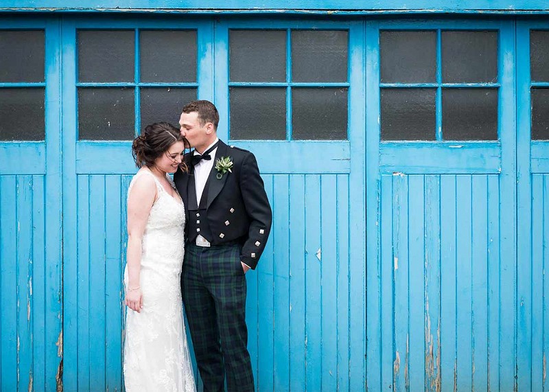 Couple hugging and kissing in front of blue garage doors