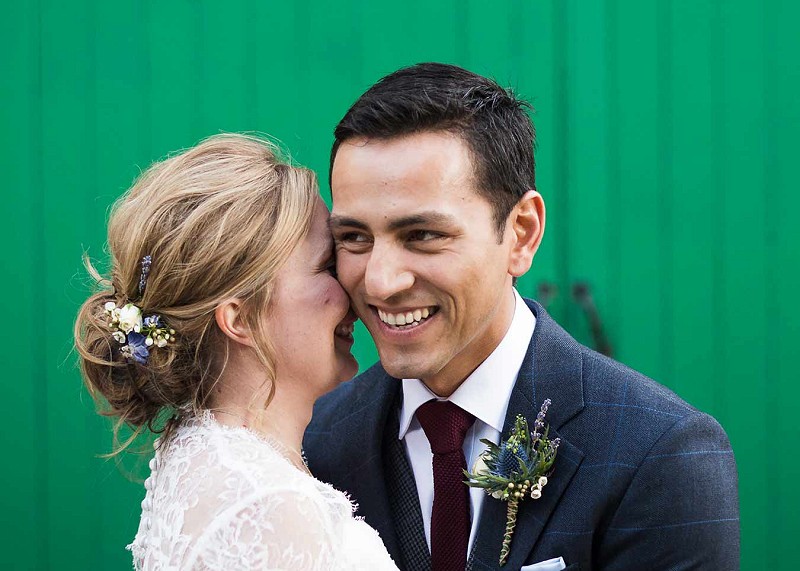 Newlyweds hugging in front of a green shed door